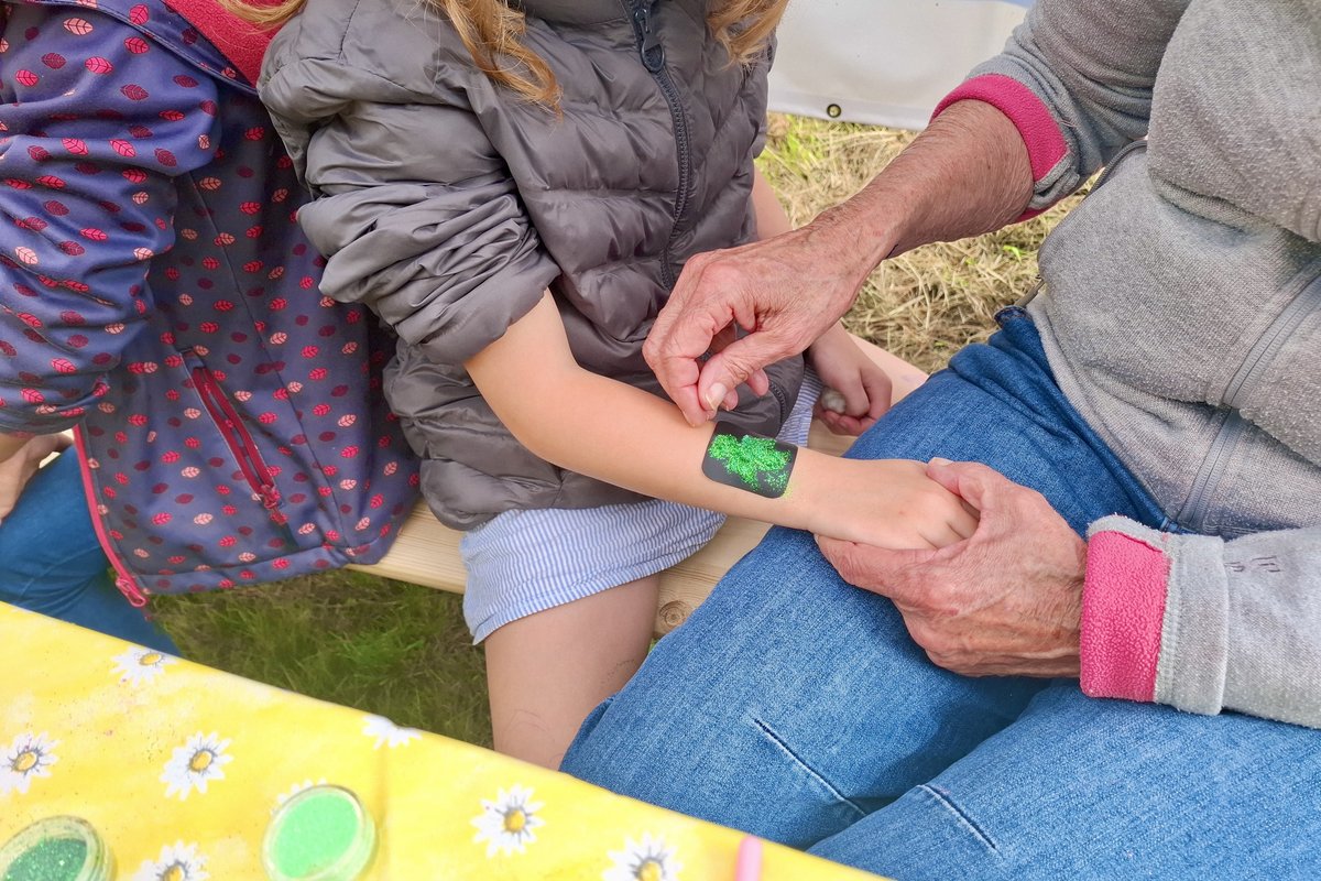 Aufmalen der Glitzertattos bei einem Kind