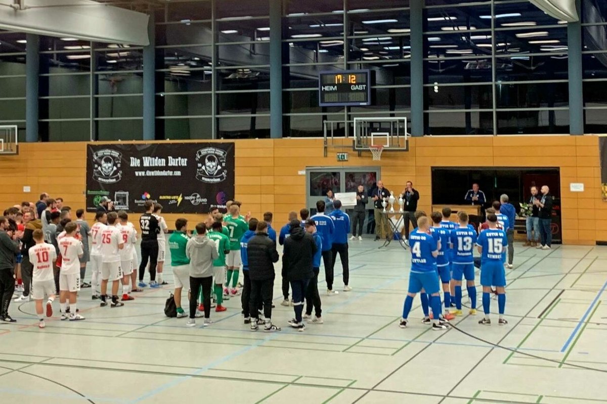 Eine Gruppe Menschen steht in einer Sporthalle.