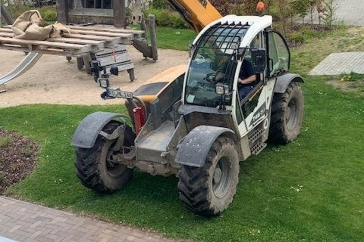Ein großer Baufahrzeug steht im Gras. Es ist bereit, seine Arbeit zu erledigen und den Bau fortzusetzen.
